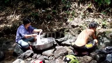 菲律宾农村社区缺乏公共供水系统设施，迫使这名妇女即使在污染的河流中也要<strong>洗衣服</strong>。